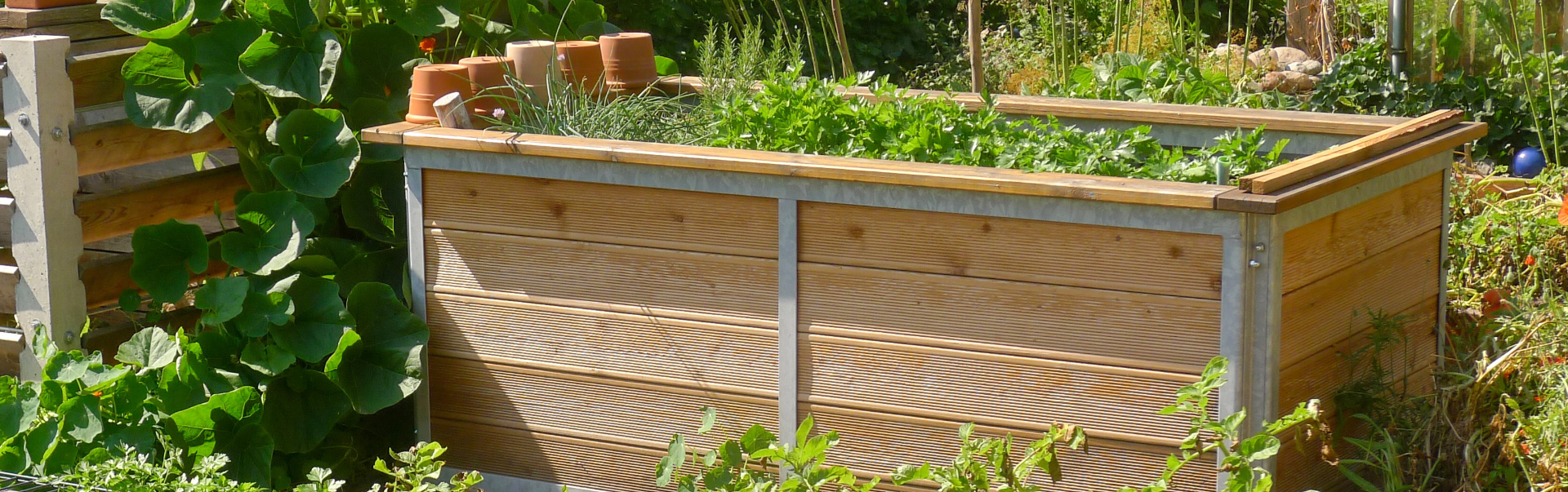 Hochbeete finden auch in kleine Gärten ihren Platz. hochbeet aus lärchenholz und metallrahmen in kleinem garten